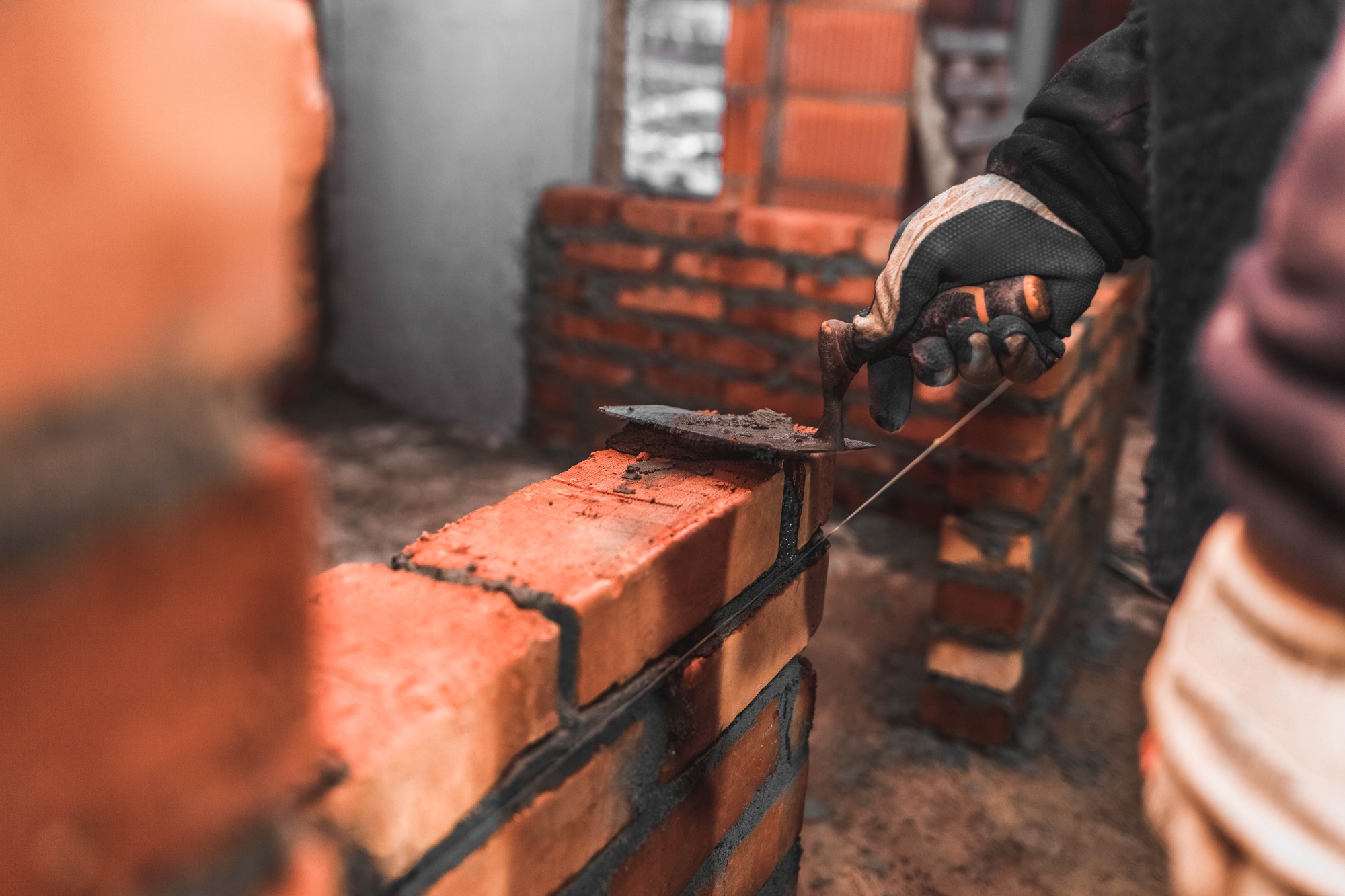 Bricklayer puts bricks to make a wall