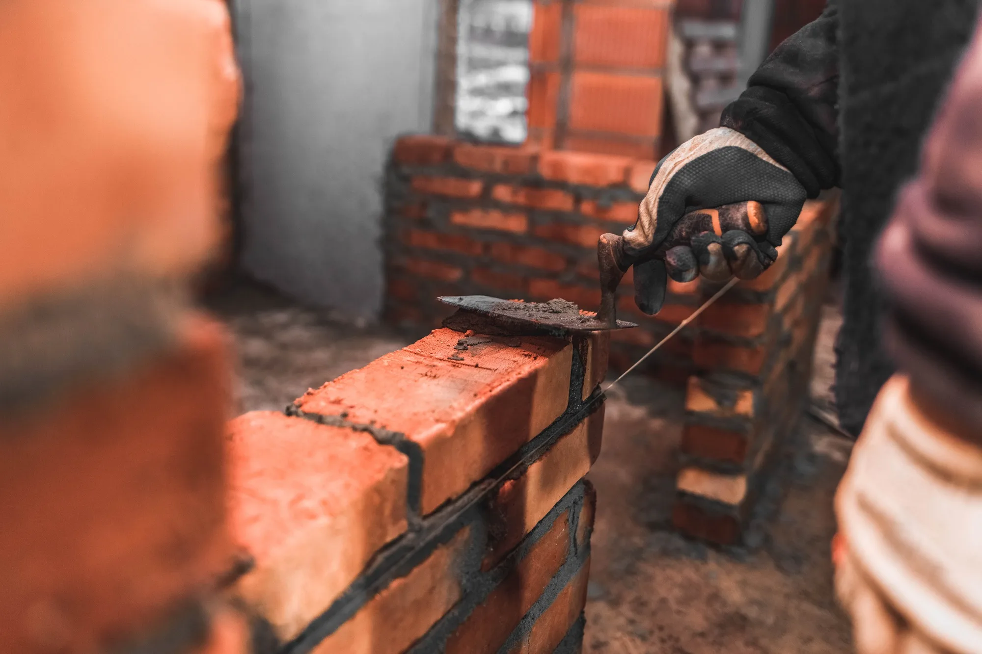 Bricklayer puts bricks to make a wall